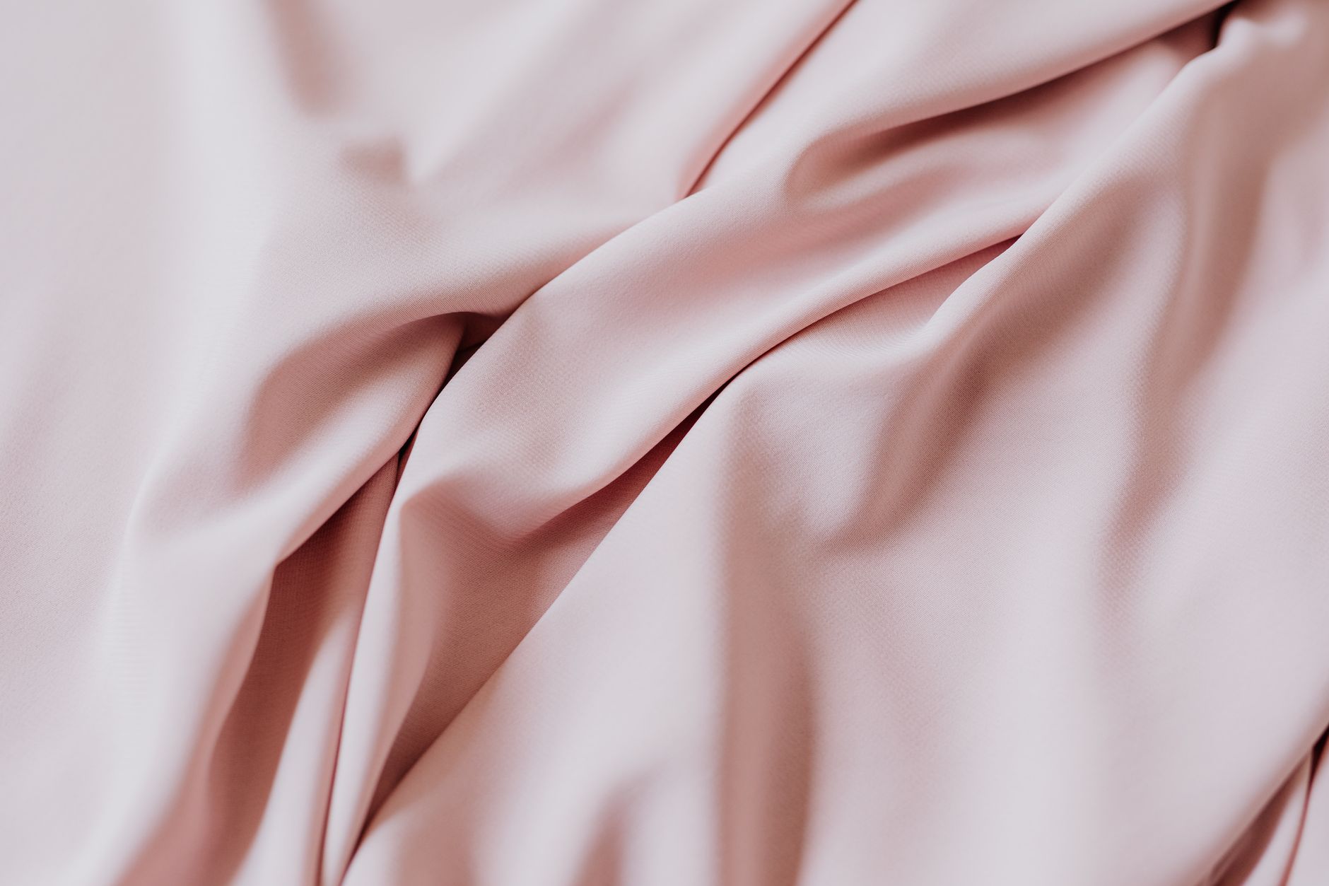 Gros plan sur un tissu rose doux avec un drapé et des plis lisses et élégants, parfait pour la conception textile.
